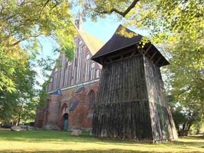 Une église historique, avec une grande structure en bois à l’avant, entourée d’arbres.