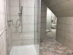 A bathroom with a shower, toilet, and patterned floor tiles. - Black-headed Gull Comfortable Holiday Residence (Dranske)