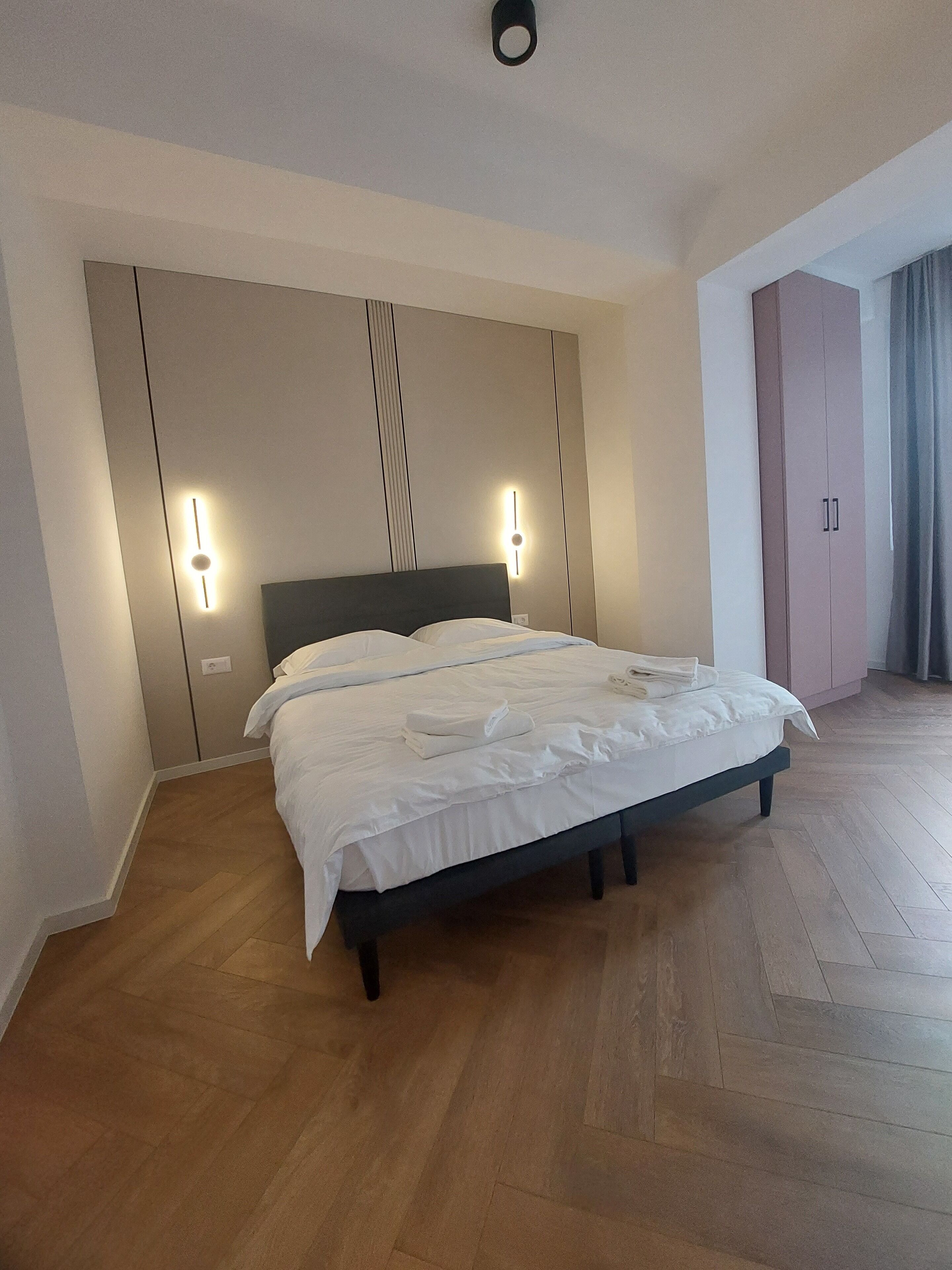 A bedroom with a bed, wooden flooring, and a wardrobe.