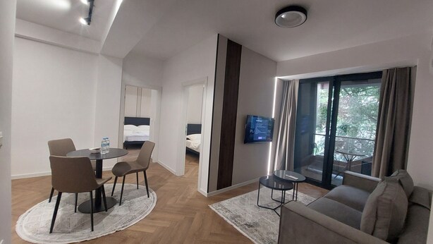 A modern hotel room with a dining area, a sofa, and a balcony with a view.