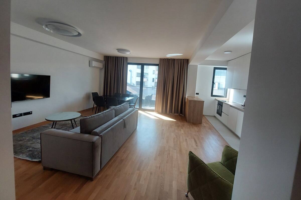 A modern living room with a sofa, dining table, and TV.