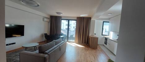 Una sala de estar moderna con un sofá, una mesa de comedor y un televisor.