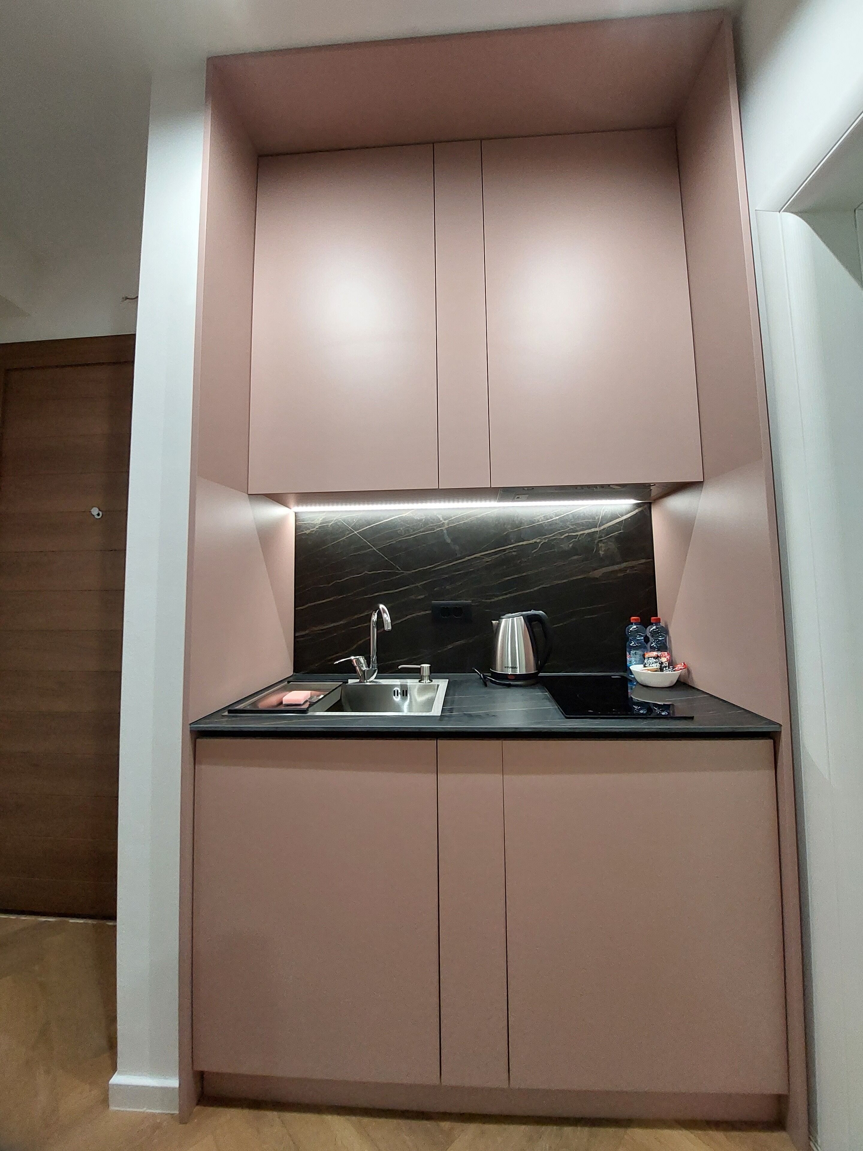 A compact kitchen with a built-in sink, a kettle, and a small countertop.