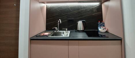 A compact kitchen with a built-in sink, a kettle, and a small countertop.