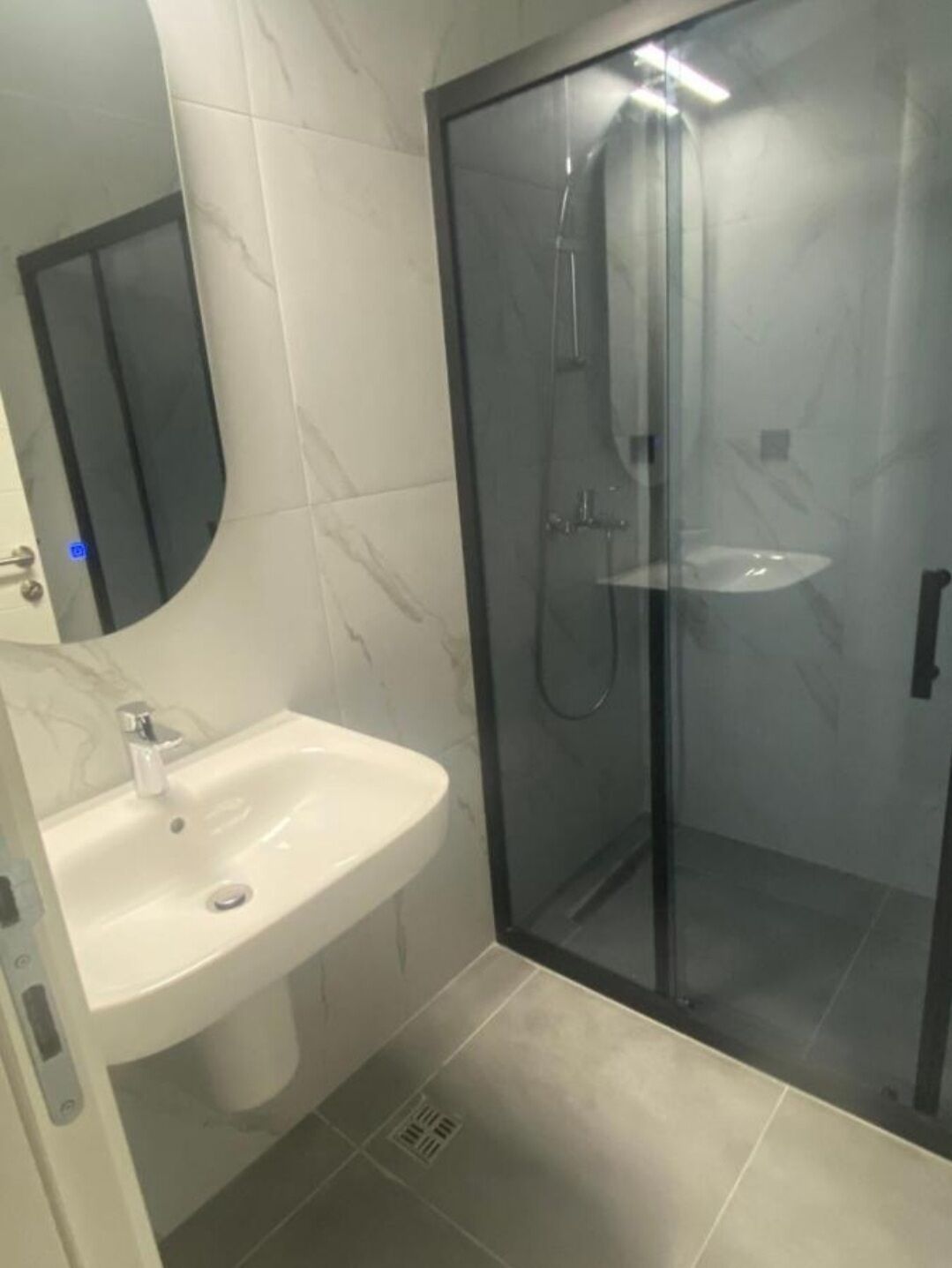 Une salle de bain avec une douche à parois de verre, un lavabo blanc et un miroir.