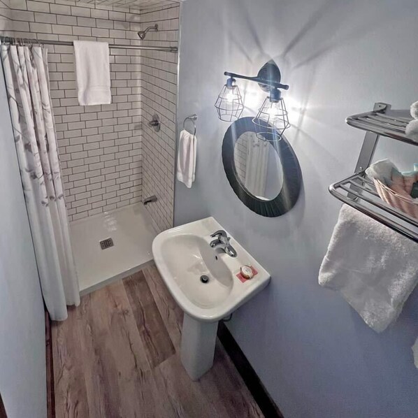 A bathroom with a shower, a sink, a mirror, and a towel rack. - Red Bay Lodge (South Bruce Peninsula)