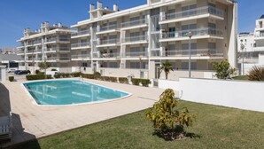 A modern multi-story residential building with a swimming pool and a well-maintained lawn. - Nazaré Beach House - 5 minutes walking to the beach (Leiria)