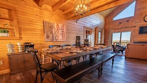 A wooden interior with a long dining table, chairs, a bench, and a chandelier. - Luxe Amish Log Cabin | 10 Acres | Private Pond | Kayak | Pizza Oven | ATV Trails (Stratford)