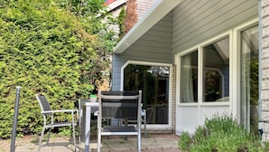 A patio with a table and chairs, a potted plant, and a building with a window. - Holiday House Viktoria at Lake Lauwersmeer (Anjum)