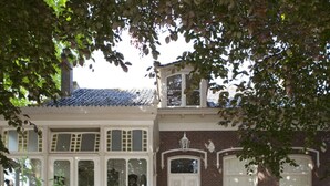 A two-story house with a brick facade, white trim, and a balcony. - Patricius Haus Comfortable Holiday Residence (Oostwoud)