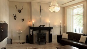 A cozy living room with a fireplace, leather sofa, and a fur rug on the floor. - Patricius Haus Comfortable Holiday Residence (Oostwoud)