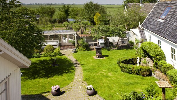 A residential property with a paved driveway, a covered outdoor seating area, and a well-maintained garden. - Patricius Haus Comfortable Holiday Residence (Oostwoud)