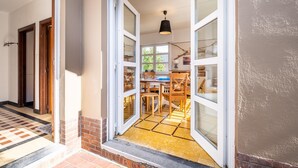 A modern entrance with a glass door leading to a dining area with a table and chairs. - Apartment in Koksijde With Terrace & Garden (Koksijde)