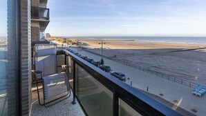A balcony with a view of a beach and a parking area. - Corner Apartment With Frontal sea View (Middelkerke)