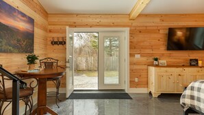 Ein Holzinterieur mit Essbereich, Fernseher und Blick durch eine Glastür.