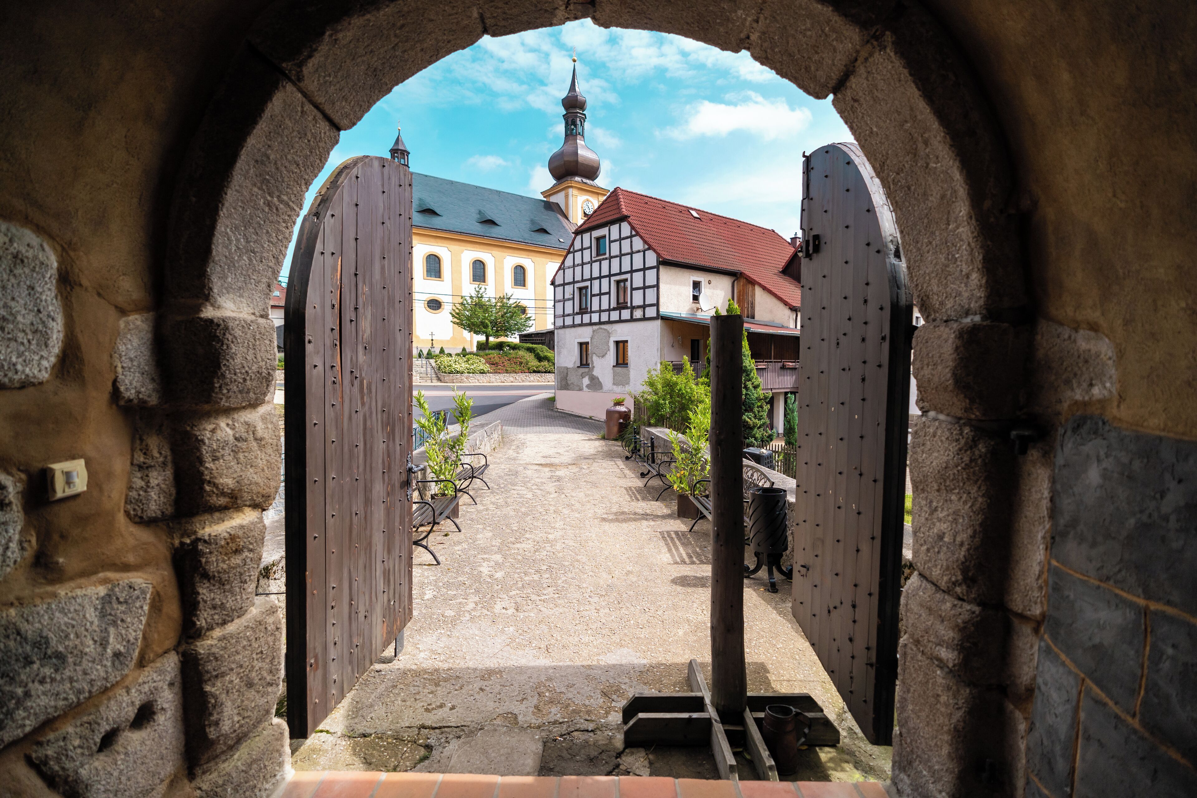 An archway leading to a courtyard with a building in the background.