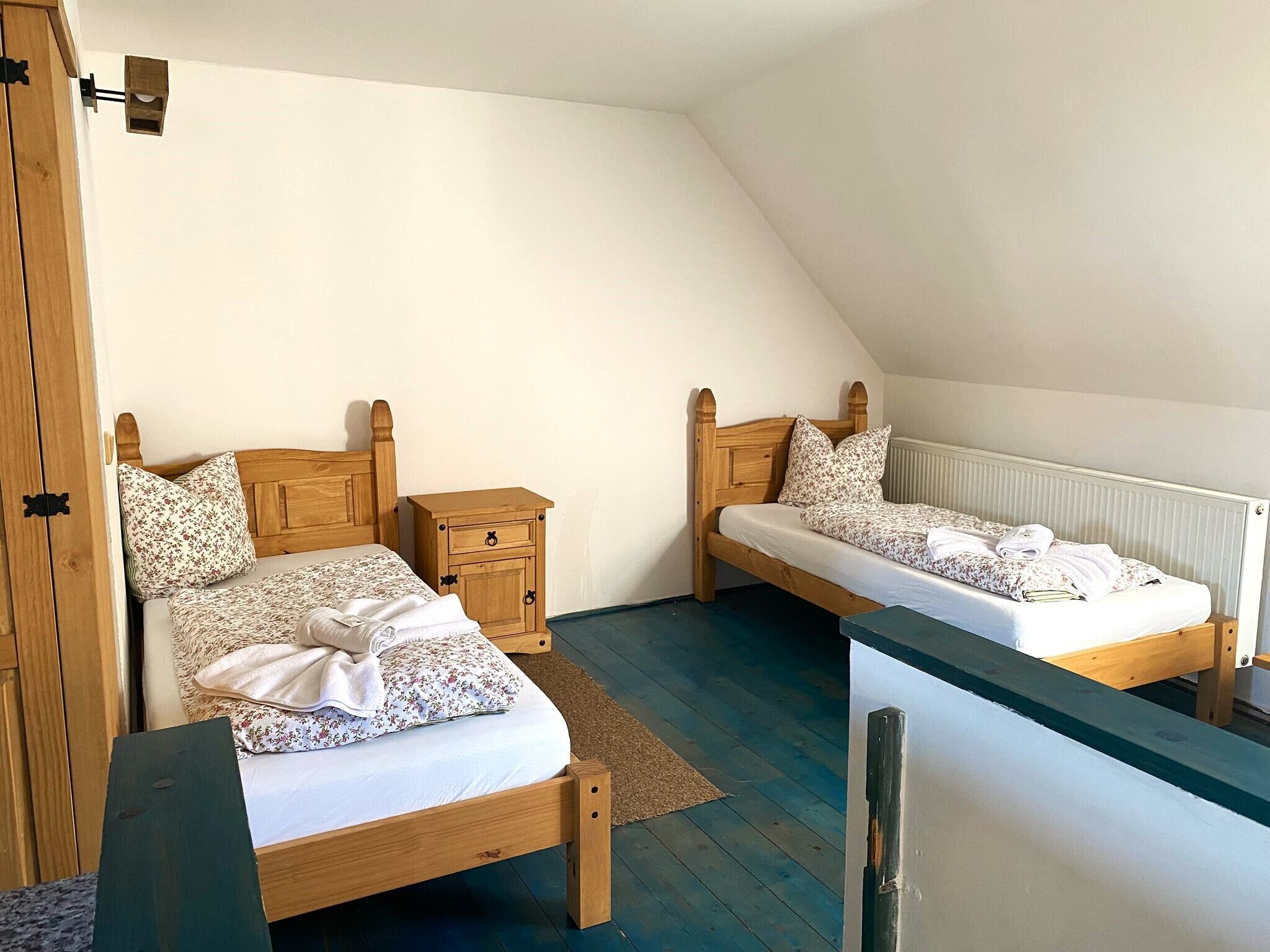 Une chambre à coucher avec deux lits en bois, une table de chevet et un radiateur.