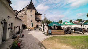 Un patio con un edificio de piedra, asientos al aire libre y sombrillas.
