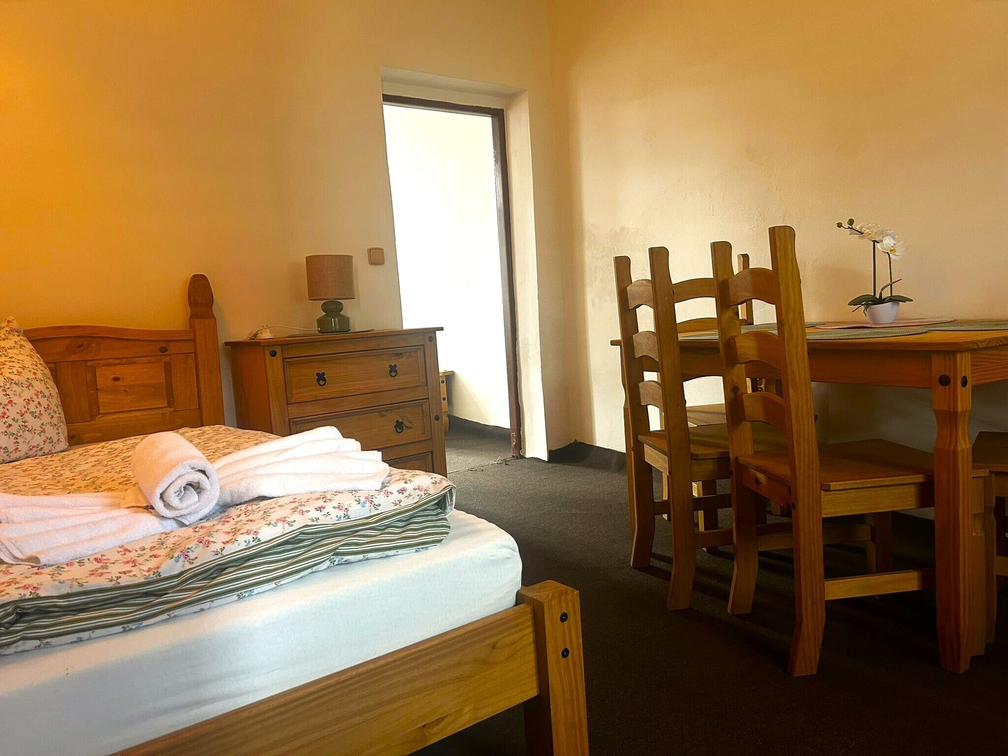 Habitació d'hotel amb un llit, un taulell de fusta, un escriptori amb una cadira i una planta en test.