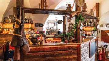 Un rústico área de bar con estantes de madera, una caja registradora antigua y diversas botellas y adornos.