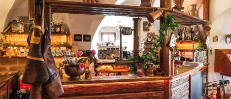 A rustic bar area with wooden shelves, a vintage cash register, and various bottles and decorations.