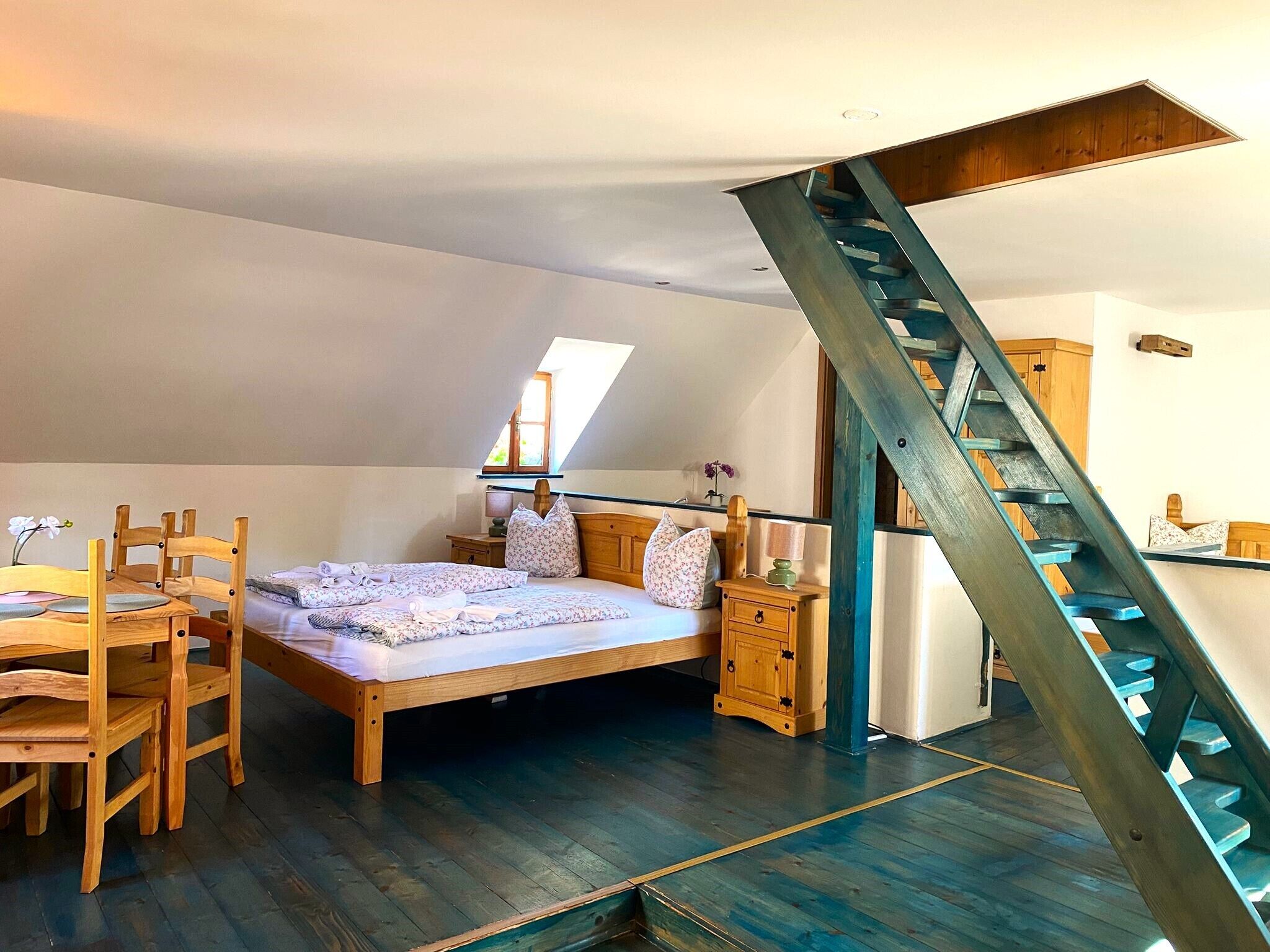 Une chambre à coucher avec un lit en bois, une chaise en bois, une table de chevet et un escalier en bois.