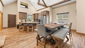 Una cocina amplia con vigas de madera, un comedor con una mesa grande y un refrigerador empotrado.