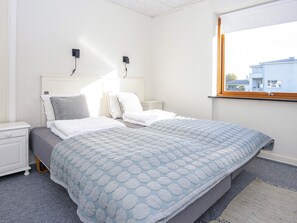 A hotel room with a bed, two bedside tables, a window with a view, and a wall-mounted light fixture. - 4 Person Holiday Home in Haderslev (Haderslev)