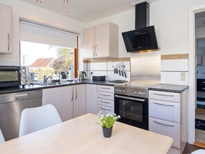 A modern kitchen with stainless steel appliances, a dining table, and a potted plant.
