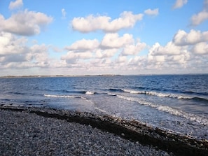 A coastal landscape with a rocky shoreline, waves, and a distant horizon. - 4 Person Holiday Home in Haderslev (Haderslev)