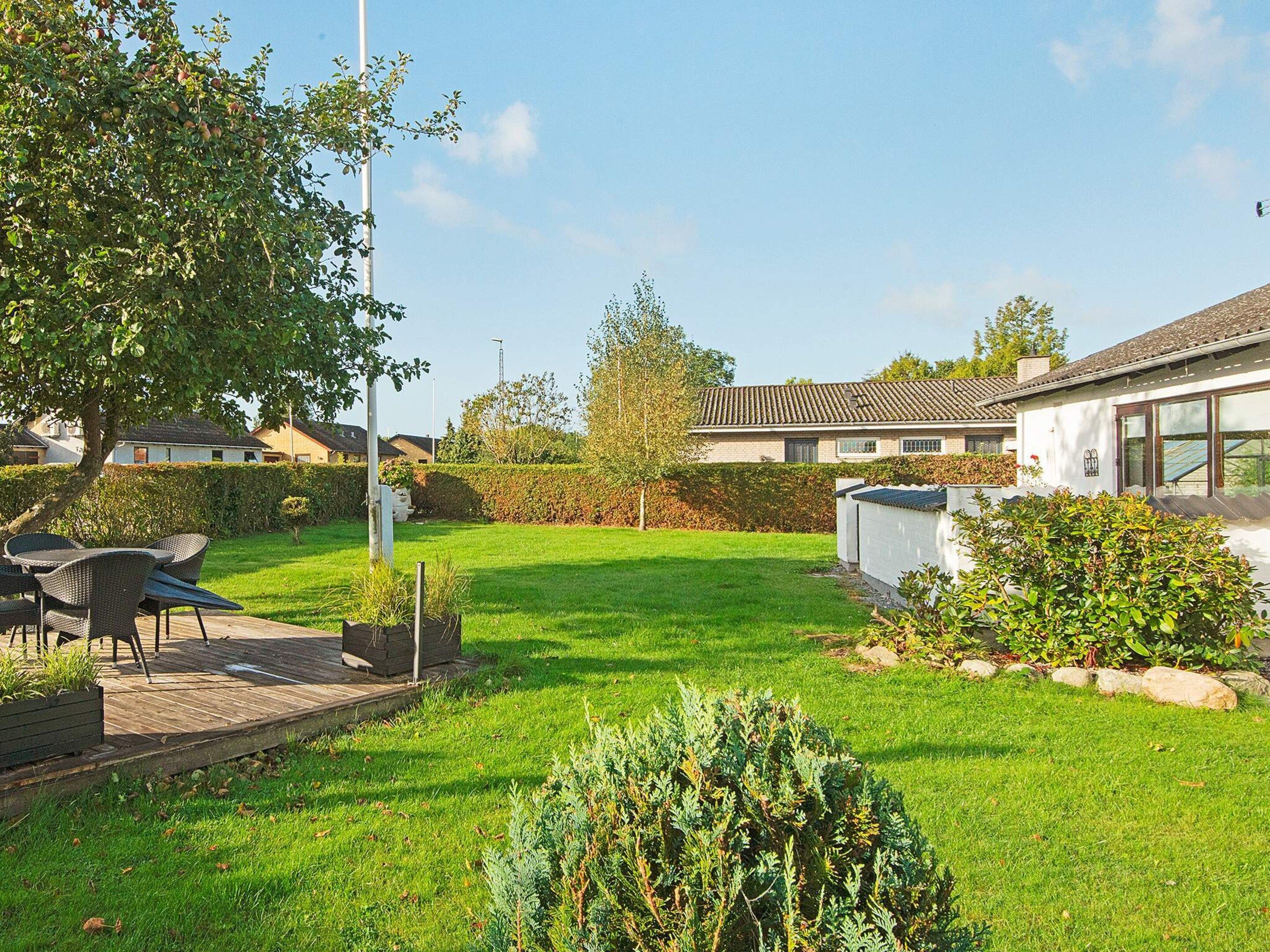 A residential property with a well-maintained lawn, outdoor seating area, and a white building with a tiled roof.