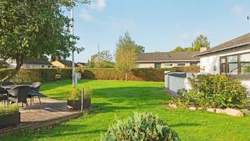 A residential property with a well-maintained lawn, outdoor seating area, and a white building with a tiled roof.