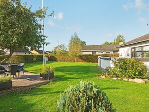 A residential property with a well-maintained lawn, outdoor seating area, and a white building with a tiled roof. - 4 Person Holiday Home in Haderslev (Haderslev)