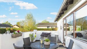 A patio with a round table and chairs, a lantern, and potted plants. - 4 Person Holiday Home in Haderslev (Haderslev)