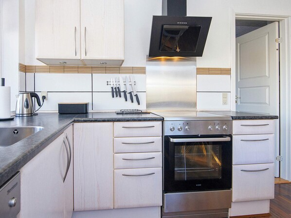 A modern kitchen with stainless steel appliances, wooden cabinets, and a built-in oven.