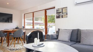 A modern living room with a grey sofa, a round coffee table, and a dining area with a wooden table and chairs. - 4 Person Holiday Home in Haderslev (Haderslev)