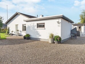 A single-story building with a white exterior, a small window, and a door. There are potted plants in front of the building. - 4 Person Holiday Home in Haderslev (Haderslev)