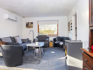 Espaço compacto com sofá, mesa redonda pequena, radiador, janela com vista e lareira a lenha.