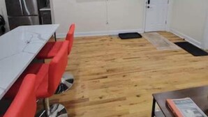 Un ambiente compatto con angolo cottura, un tavolo da pranzo con sedie rosse, una TV a schermo piatto montata a parete e un tavolino con un libro.