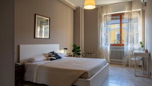 A bedroom with a bed, bedside table, lamp, window with curtains, and a plant. - In the heart of Pescara, Hope will be your home just 5 minutes from the sea. (Pescara)