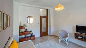 A modern living room with a sofa, a chair, a TV, and a wooden cabinet. - In the heart of Pescara, Hope will be your home just 5 minutes from the sea. (Pescara)
