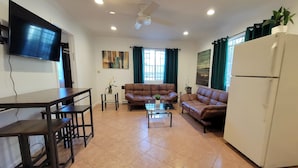A living room with a TV, two sofas, a coffee table, a dining table, and a refrigerator. - Beverlywood 2 bedroom guesthouse. 5 minutes to Rodeo Drive!  (Beverly Hills)