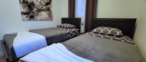 Habitación de hotel con dos camas, un cuadro abstracto grande en la pared y una ventana con cortinas.