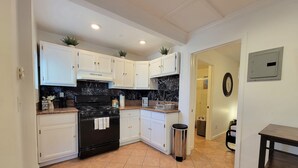 A kitchen with white cabinets, a black stove, and a tiled floor. - Beverlywood 2 bedroom guesthouse. 5 minutes to Rodeo Drive!  (Beverly Hills)