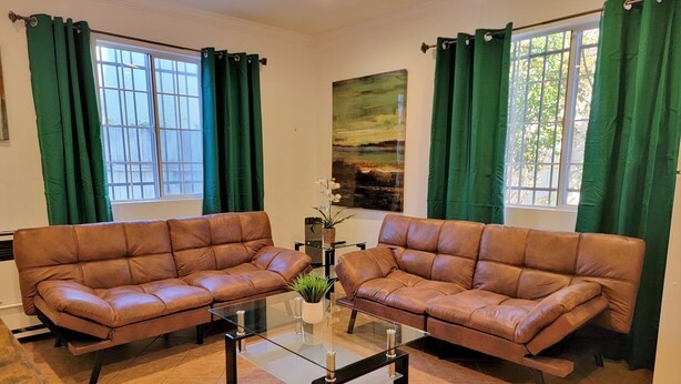 A living room with two brown leather sofas, a glass coffee table, and green curtains. - Beverlywood 2 bedroom guesthouse. 5 minutes to Rodeo Drive!  (Beverly Hills)