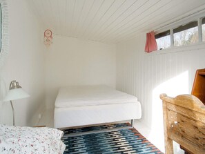 A small, sparsely furnished room with a bed, a desk, a lamp, and a window with a curtain. - 7 Person Holiday Home in Sjaellands Odde (Sjællands Odde)