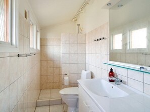 A bathroom with a toilet, a glass shower enclosure, and a white sink with a soap dispenser. - 7 Person Holiday Home in Sjaellands Odde (Sjællands Odde)