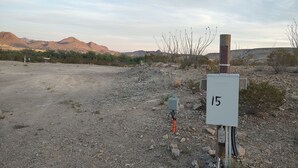 A utility box labeled "15" in a rocky, desert-like environment with sparse vegetation and distant mountains. - Longhorn Ranch Motel - Full Hook-Up RV Park with Power and Sewer (Alpine)