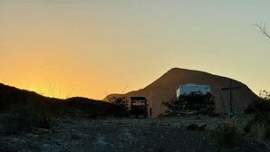 A dirt road leading to a building with a cross, surrounded by sparse vegetation and a mountain in the background. - Longhorn Ranch Motel - RV Park with Power and No Sewer (Alpine)