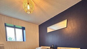Un dormitorio con dos camas, una ventana, una lámpara de techo y un espejo.